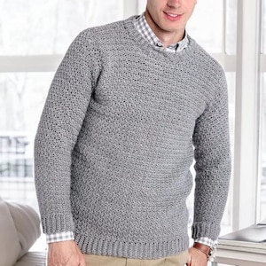 Op de afbeelding: Een grijze gebreide trui met een ronde hals en lange mouwen. De trui heeft een textuurpatroon.