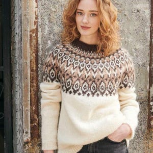 May include: A white sweater with a brown and pink geometric pattern around the neckline. The sweater is made of a soft, fuzzy material.