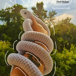 Może przedstawiać: Wzór na amigurumi węża na szydełku, w jasnofioletowym kolorze, z tekstem "DIGITAL PATTERN" i "Sustainacraft" na obrazku.