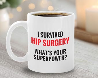 May include: White ceramic mug filled with coffee, featuring the text "I SURVIVED HIP SURGERY WHAT'S YOUR SUPERPOWER?" in black and red lettering. The mug has a curved handle and is set against a blurred background.
