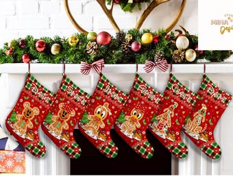 Op de afbeelding: Zes rode kerstsokken met peperkoekkarakterontwerpen en gepersonaliseerde namen. Elke sok heeft een groen-rode geruite manchet en een decoratieve strik. De sokken hangen aan een witte schoorsteenmantel versierd met slingers en ornamenten.
