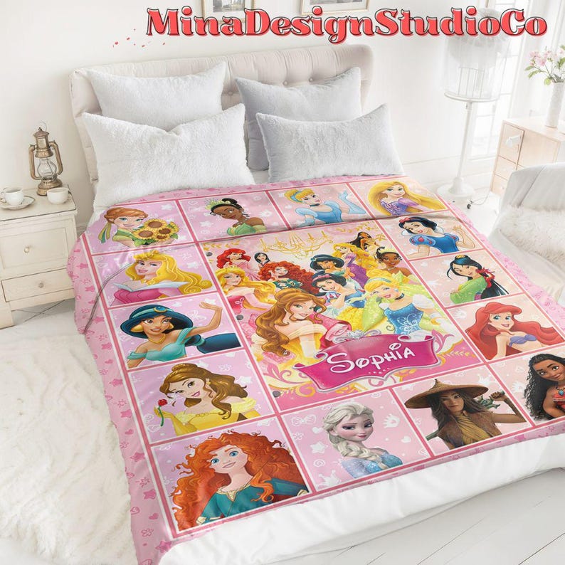 Puede incluir: Manta de forro polar rosa con un collage de princesas Disney, incluyendo Cenicienta, Ariel, Bella y Mulan. La manta tiene un fondo rosa con estrellas blancas y el nombre "Sophia" en una pancarta dorada.
