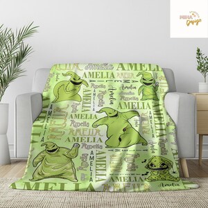 May include: A light green blanket featuring multiple images of a cartoon character and the name "Amelia" in various fonts. The blanket has a repeating pattern of the character and the name, creating a personalized design.