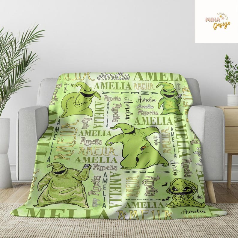 May include: A light green blanket featuring multiple images of a cartoon character and the name "Amelia" in various fonts. The blanket has a repeating pattern of the character and the name, creating a personalized design.