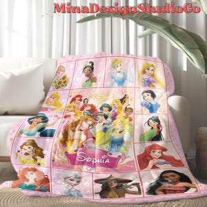 Puede incluir: Manta de forro polar rosa con un collage de princesas Disney, incluyendo Cenicienta, Blancanieves, Ariel y Moana. La manta tiene un fondo rosa con bordes blancos alrededor de cada imagen de princesa. El nombre "Sophia" est&aacute; escrito en una pancarta rosa en la parte inferior de la manta.