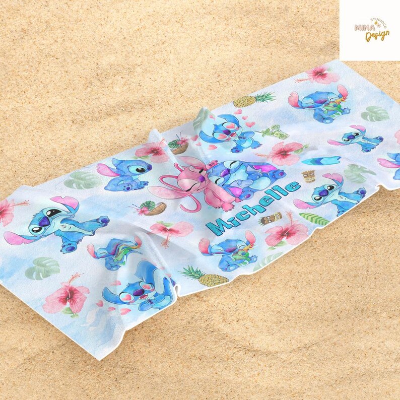 May include: A white beach towel featuring a repeating pattern of the character Stitch from the animated film Lilo & Stitch. The design includes Stitch in various poses, pink hibiscus flowers, and pineapples. The name "Michelle" is printed in blue script.