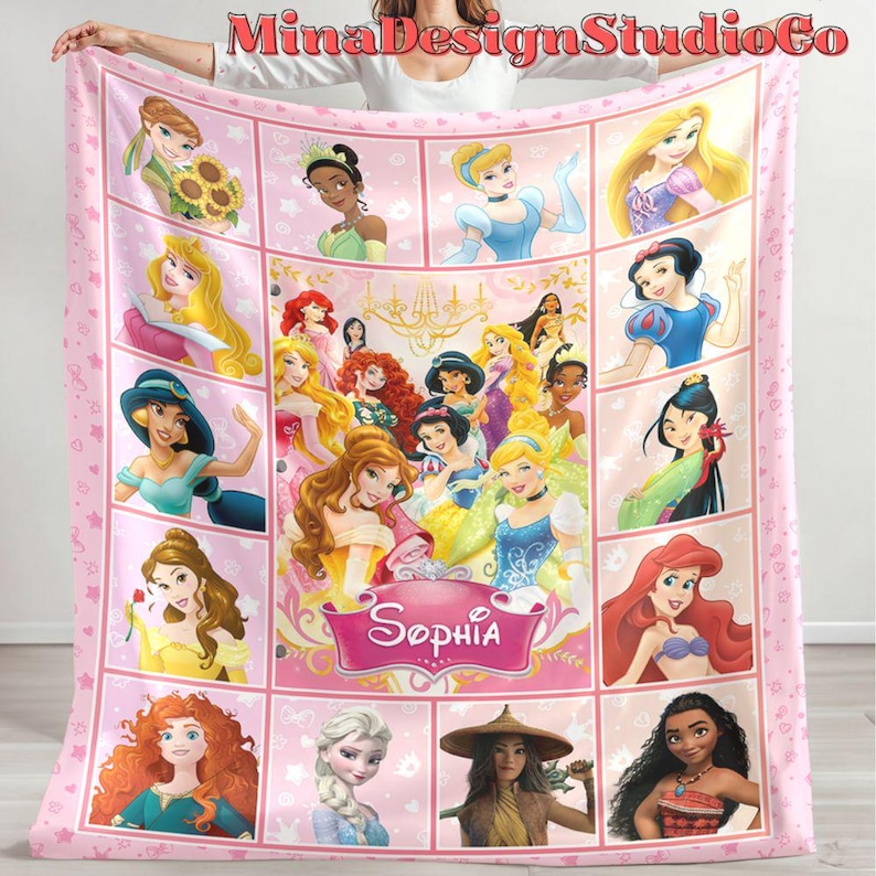 Puede incluir: Manta de forro polar rosa con un collage de princesas Disney, incluyendo Cenicienta, Ariel, Bella y Moana. La manta tiene un fondo rosa con estrellas blancas y el nombre "Sophia" en una fuente decorativa.