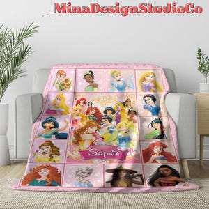 Puede incluir: Manta de forro polar rosa con un collage de princesas Disney, incluyendo Cenicienta, Blancanieves, Ariel y Bella. La manta tiene un fondo rosa con un borde blanco y el nombre "Sophia" en una pancarta blanca.
