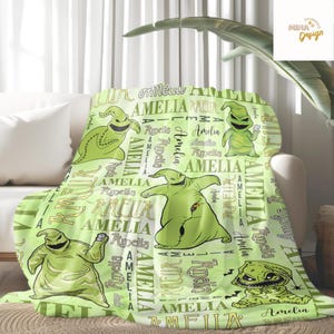 May include: A light green blanket featuring multiple images of a cartoon character, with the name "Amelia" and other text in a repeating pattern. The blanket is draped over a white sofa.