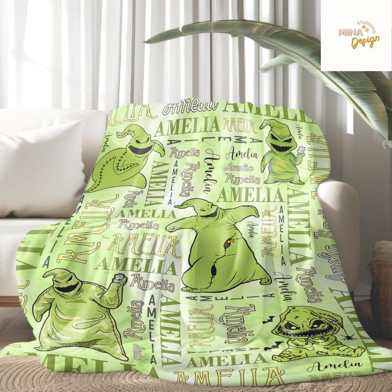 May include: A light green blanket featuring multiple images of a cartoon character, with the name "Amelia" and other text in a repeating pattern. The blanket is draped over a white sofa.