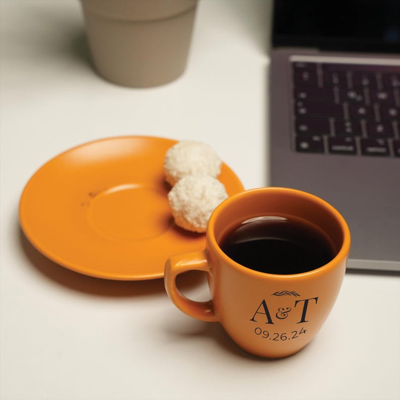 a cup of coffee next to a plate with a doughnut on it