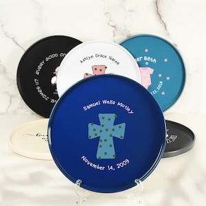 Puede incluir: Una bandeja redonda azul con una cruz blanca con lunares verdes. La bandeja tiene el texto "Samuel Wells Motley" y "November 14, 2009" escrito en ella.