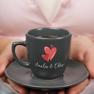a person holding a black coffee cup with a red heart on it