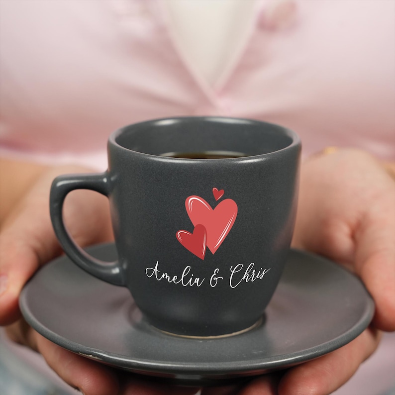a person holding a black coffee cup with a red heart on it