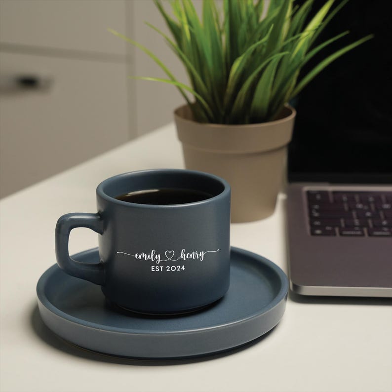 a cup of coffee sitting on a saucer next to a laptop