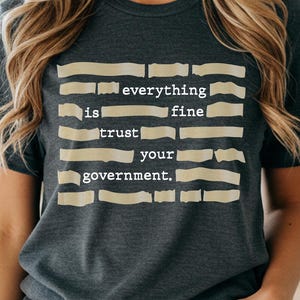 Puede incluir: Una taza de cerámica blanca con un asa negra y el texto "But First, Coffee" en negrita negra. La taza está sobre una superficie de madera. La taza mide aproximadamente 10 cm de alto.