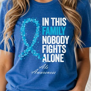 May include: A royal blue t-shirt with the text "IN THIS FAMILY NOBODY FIGHTS ALONE" and "Als Awareness" in white. A light blue ribbon made of small hearts is on the left side of the text. The bottom of the shirt has the text "HEATHER TRUE ROYAL".