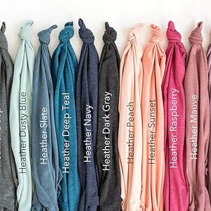 May include: A collection of folded t-shirts in various colors, including Ash, Heather Athletic, Heather Deep, Heather Dusty Blue, Heather Slate, Heather Deep Teal, Heather Navy, Heather Dark Gray, Heather Peach, Heather Sunset, Heather Raspberry, Heather Mauve, Heather Orchid, Heather Maroon, and Heather Cardinal.