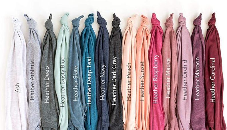May include: A collection of folded t-shirts in various colors, including Ash, Heather Athletic, Heather Deep, Heather Dusty Blue, Heather Slate, Heather Deep Teal, Heather Navy, Heather Dark Gray, Heather Peach, Heather Sunset, Heather Raspberry, Heather Mauve, Heather Orchid, Heather Maroon, and Heather Cardinal.