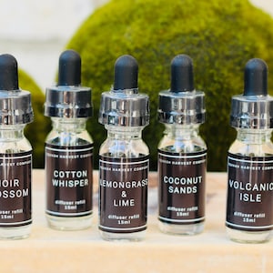 May include: Five glass diffuser refill bottles with black droppers and labels. The labels read "Noir Blossom", "Cotton Whisper", "Lemongrass & Lime", "Coconut Sands", and "Volcanic Isle". Each bottle contains 15ml.