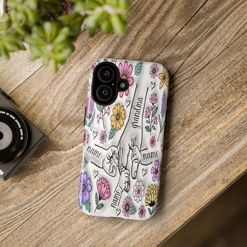Peut inclure: Coque de t&eacute;l&eacute;phone blanche avec un motif floral et les mots "grandma" et "name" r&eacute;p&eacute;t&eacute;s. Le motif pr&eacute;sente des fleurs roses, violettes, jaunes et vertes.