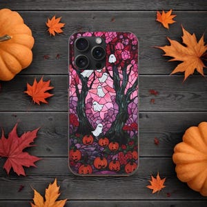 Può includere: Una custodia per telefono in vetro colorato rosa e viola a tema Halloween. La custodia presenta due alberi con fantasmi che volano intorno a loro e zucche alla base degli alberi.