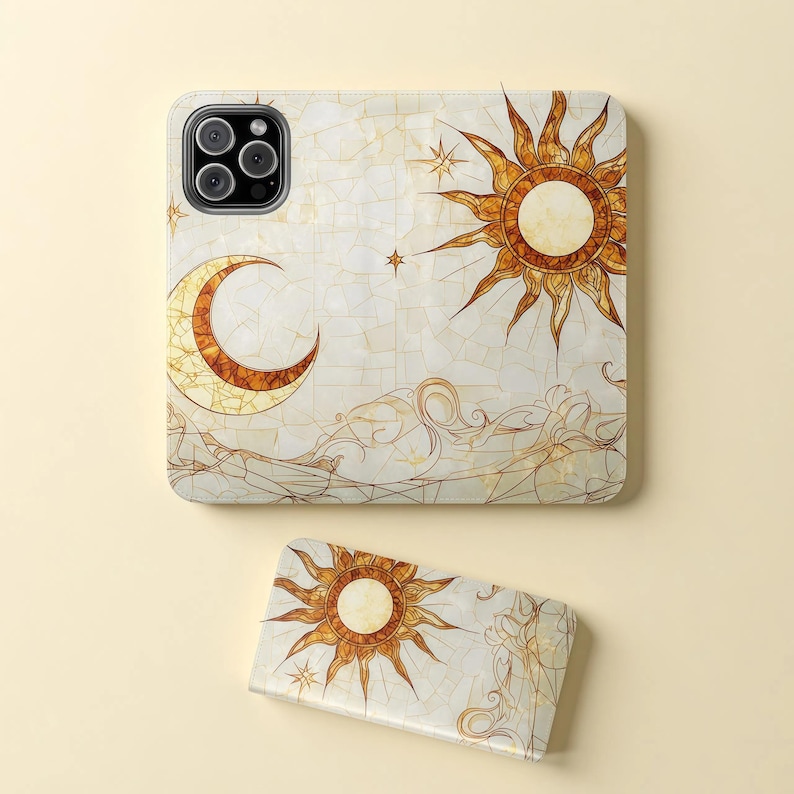 Op de afbeelding: Een telefoonhoesje en een bijpassende telefoonhouder met een hemels ontwerp. Het ontwerp bevat een zon, maan en sterren in goud- en bruintinten op een witte achtergrond. De hoes en houder hebben een moza&iuml;ekpatroon.