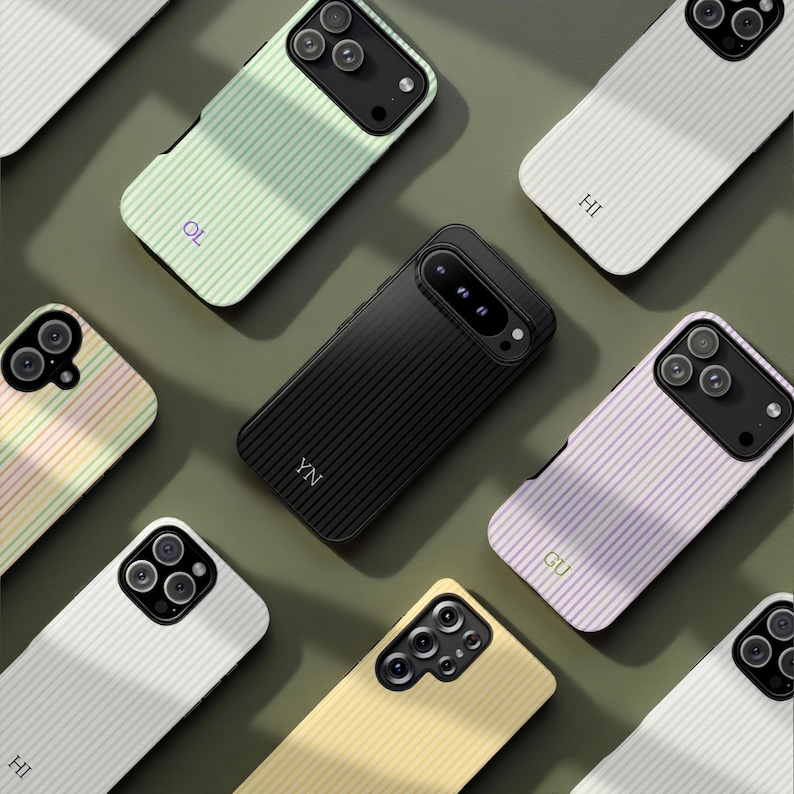 May include: A collection of smartphone cases in various colors, including black, white, yellow, green, and lavender. Each case features a striped design and a camera cutout. Some cases have initials printed on them.