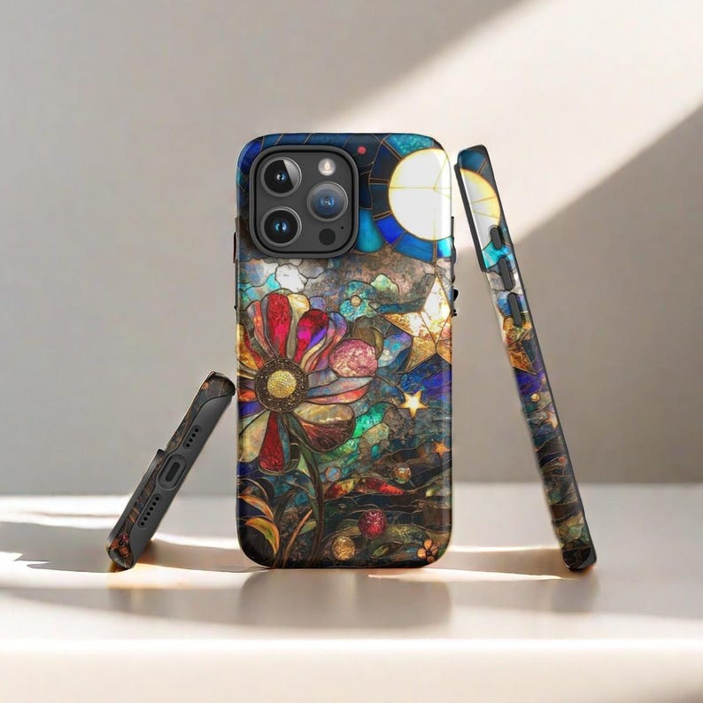 Op de afbeelding: Een zwarte telefoonhoes met een glas-in-loodontwerp met een kleurrijke bloem en sterren. De hoes heeft een uitsparing voor de camera's van de telefoon.