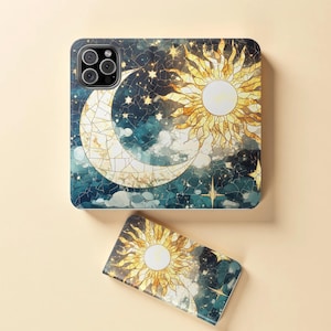 Op de afbeelding: Een telefoonhoesje en een kleiner accessoire met een hemels ontwerp. Het ontwerp bevat een maan, een stralende zon, sterren en wolken tegen een donkerblauwe en blauwgroene achtergrond. De zon en maan hebben een glas-in-lood effect.
