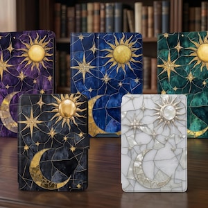 Puede incluir: Una colección de diarios decorativos con diseños celestiales. Cada diario presenta un motivo de sol, luna y estrella en dorado sobre fondos morados, azules, negros, verdes y blancos. Los diarios se exhiben sobre una superficie de madera.
