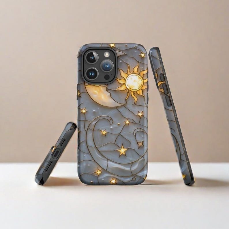 May include: A phone case with a stained glass design featuring a crescent moon, sun, and stars on a gray background.