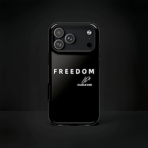May include: Black phone case with the word "FREEDOM" in white, along with a signature. The case has a glossy finish and a camera module with three lenses. The background is a dark, solid color.