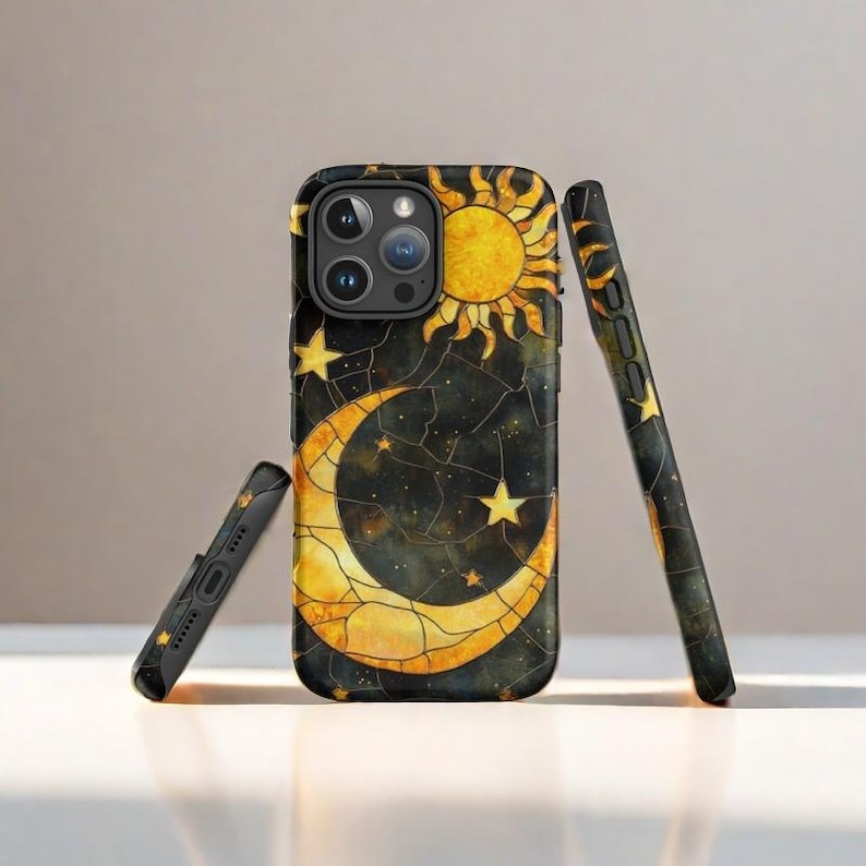 May include: A black phone case with a stained glass design featuring a crescent moon, sun, and stars on a dark blue background.