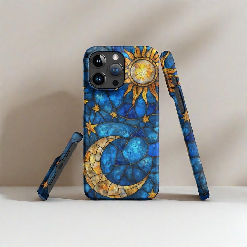 May include: A blue and gold phone case with a stained glass design of a sun and moon with stars. The case is made for an iPhone.