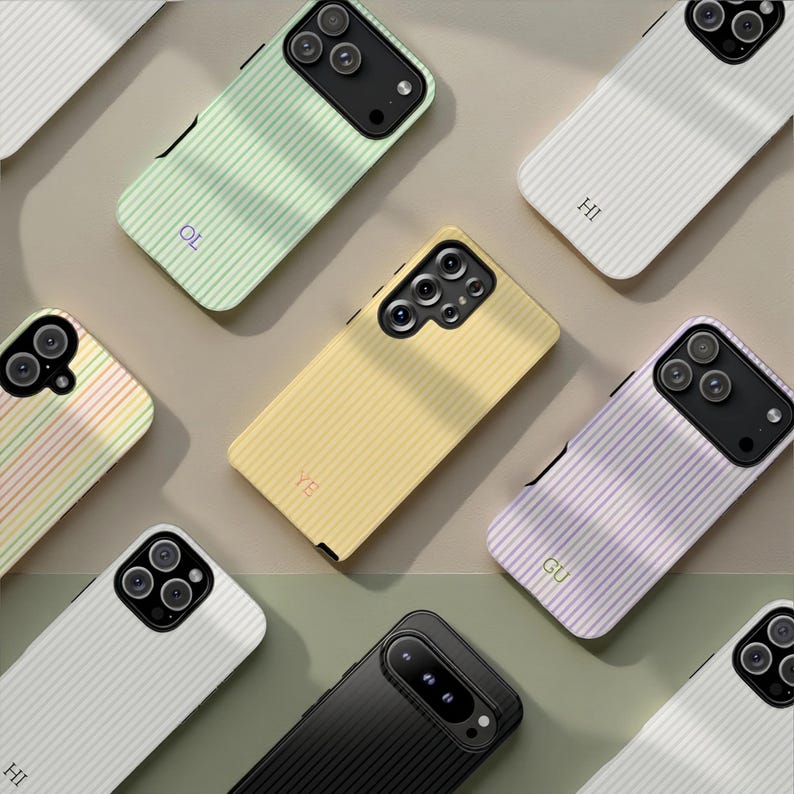 May include: A collection of colorful phone cases with a ribbed texture. Cases are in various colors, including white, black, yellow, green, and purple. Some cases have initials printed on them. The cases are designed to fit different phone models.