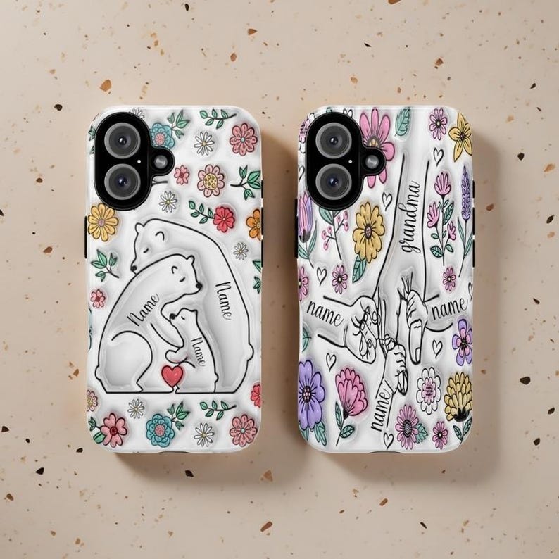 Peut inclure: Deux coques de t&eacute;l&eacute;phone avec un motif floral. Une coque repr&eacute;sente un ours polaire blanc avec un ourson et le texte "Nom" sur chaque ours. L'autre coque repr&eacute;sente une main tenant une main plus petite avec le texte "Grand-m&egrave;re" et "Nom" sur chaque main.