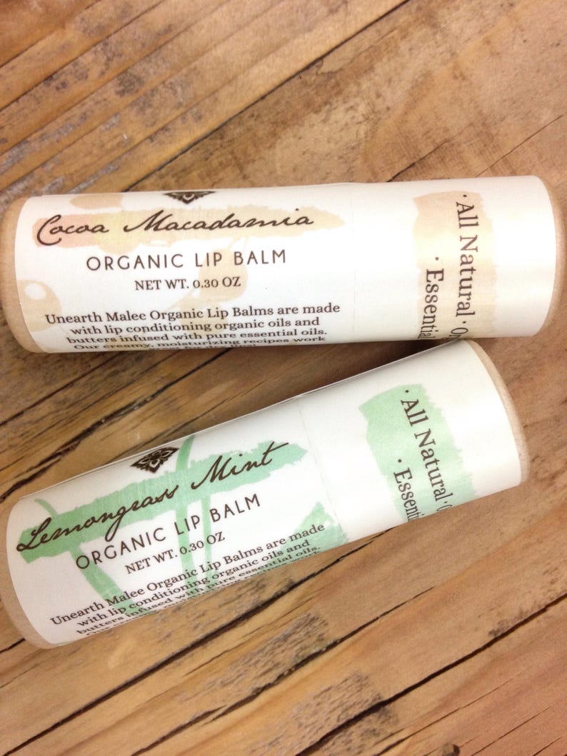 May include: Two tubes of organic lip balm, one with a cocoa macadamia scent and the other with a lemongrass mint scent. Both tubes are labelled "All Natural" and "Essential Oils" and have a net weight of 0.30 oz.