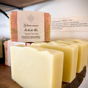 May include: Four bars of white soap with a pink and gold label that reads "Calamansi White Tea Vitamin C Face Soap Palm-Oil Free * Organic Ingredients No Chemical Preservatives * Vegan"
