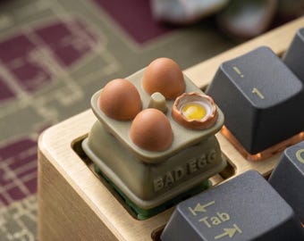 Copritasto artigianale a forma di cartone dell'uovo rotto, ideale per gli amanti dei copritasti e per gli appassionati di tecnologia, perfetto come regalo per la configurazione di gioco, per PC o ufficio.