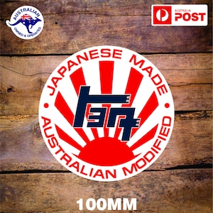 以下が含まれることがあります： 赤と白のストライプ、青い日本の車のロゴ、そして周囲に「Japanese Made Australian Modified」というテキストが書かれた白い円形のステッカー。ステッカーの直径は100mmです。