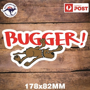 Könnte beinhalten: Ein Aufkleber mit einem braunen Cartoon-Hund, der mit ausgestreckten Armen liegt und einen Stachelhalsband trägt. Das Wort "BUGGER!" steht in roten, fetten Buchstaben darüber. Der Aufkleber misst 178x82mm.
