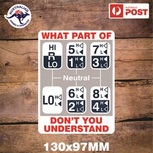 May include: A white sign with black text and graphics that reads "What part of" and shows a diagram of a gear shifter with the letters "H", "R", "L", "LO", and numbers 1 through 8. The sign also reads "Don't you understand" and "130x97MM".