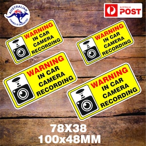 Può includere: Quattro cartelli di avvertimento gialli e neri con il testo "WARNING IN CAR CAMERA RECORDING" e un'icona di una telecamera in bianco e nero. I cartelli misurano 78 mm x 38 mm e 100 mm x 48 mm.