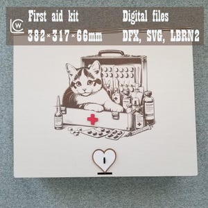 Puede incluir: Un botiquín de primeros auxilios de madera con cierre en forma de corazón. Presenta una ilustración en blanco y negro de un gato dentro de un maletín médico con varios suministros médicos. El texto "First aid kit" y "Digital files" están en la parte superior. Dimensiones: 38,2 x 31,7 x 6,6 cm.