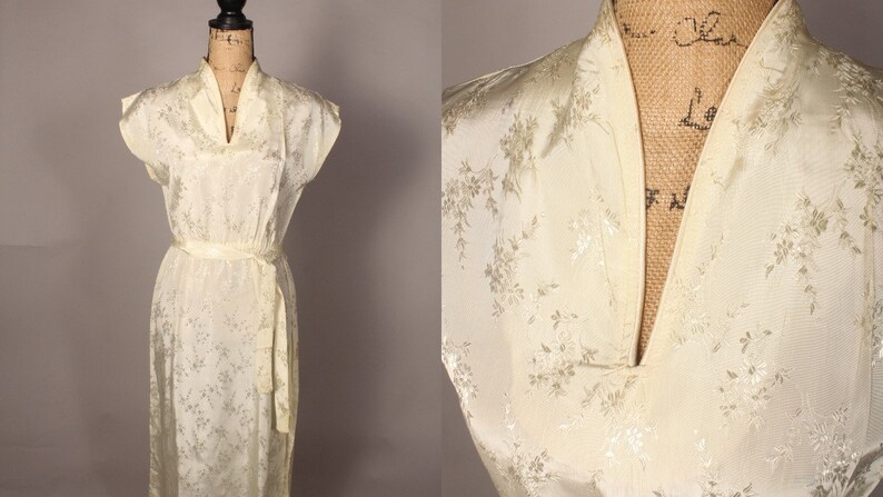 May include: A white satin dress with a floral pattern and a mandarin collar. The dress has a sash tie at the waist and short sleeves.