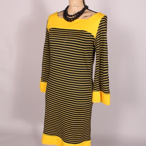 Puede incluir: Un vestido de rayas amarillas y negras con cuello y pu&ntilde;os amarillos. El vestido est&aacute; en un maniqu&iacute;.