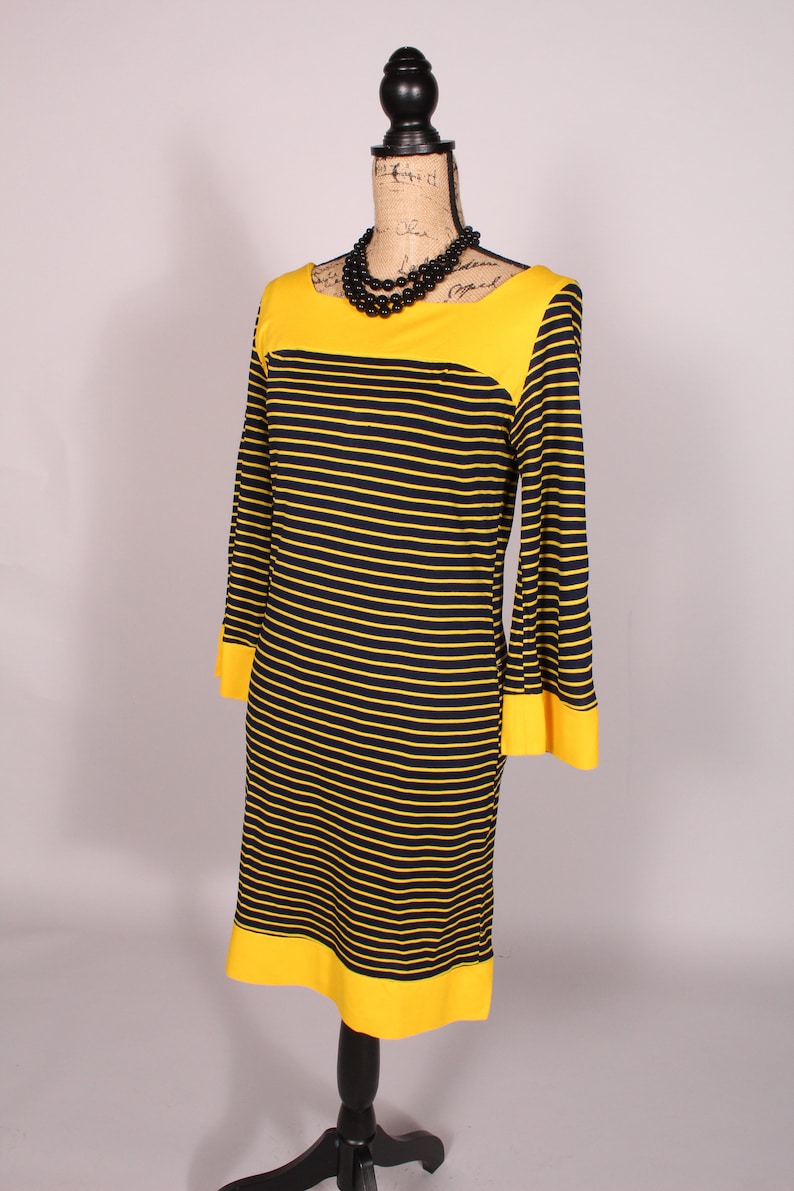Puede incluir: Un vestido de rayas amarillas y negras con cuello y pu&ntilde;os amarillos. El vestido est&aacute; en un maniqu&iacute;.
