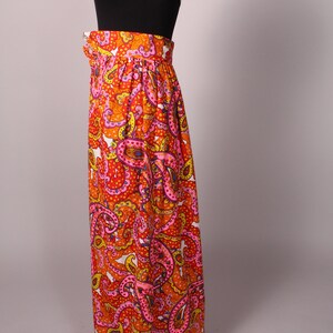 May include: A long, flowing skirt with a paisley print in shades of orange, pink, and yellow. The skirt has a high waist and a gathered design.