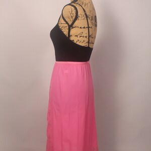 May include: A pink slip skirt with a lace trim. The skirt is on a mannequin and is made of a silky material.